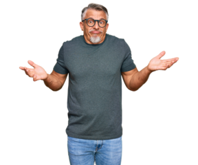 Middle age grey-haired man wearing casual clothes and glasses clueless and confused expression with arms and hands raised. doubt concept.