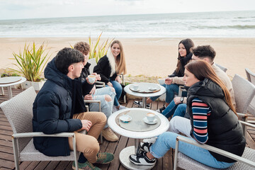 Group of friends sitting in outdoor cafe on seashore
