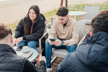 Group of friends sitting in outdoor cafe on seashore
