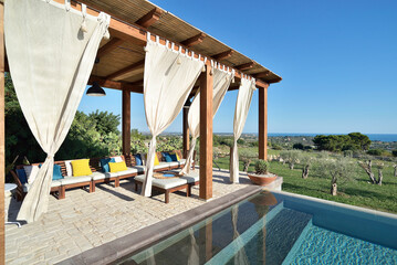 Piscina con gazebo e arredamento con divani e lettini