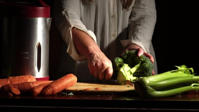 Woman chopping broccoli vegetables for soup maker 