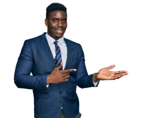 Handsome business black man wearing business suit and tie amazed and smiling to the camera while presenting with hand and pointing with finger.