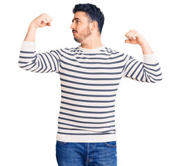 Young hispanic man wearing casual clothes showing arms muscles smiling proud. fitness concept.