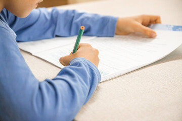 Caucasian elementary school child doing homework at the end of the school day. Close up and copy space. - obrazy, fototapety, plakaty