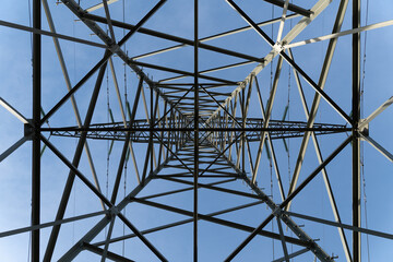 High voltage pylons against a slightly clouded blue sky. 
