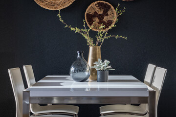 Dramatic dining room with black wall covering and woven baskets, table with trio of decorative...