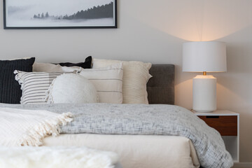 Relaxing bedroom detail of grey, black and white striped pillows and layers of bedding on large bed...