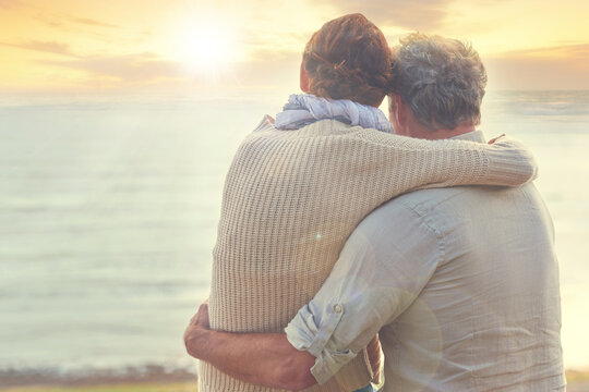 Old couple, hug and sunset on sea at the beach with care, support and trust in marriage or retirement. Back, man and woman in embrace with love, kindness and gratitude for vacation or holiday