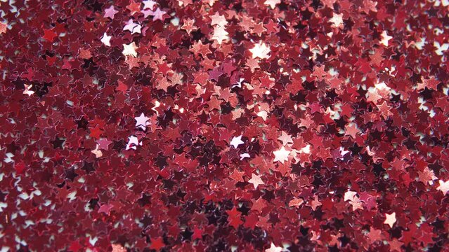 Red metal stars. Colorful particles such as confetti or sparkles fall on a silver holiday background. Shiny texture. Particle background. Shining sparkles.
