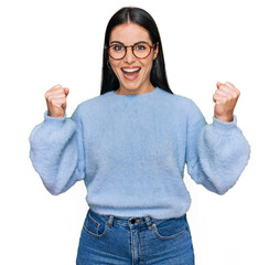 Young hispanic woman wearing casual clothes and glasses celebrating surprised and amazed for...