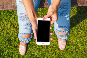 Fashionable young woman holding smartphone with blank screen