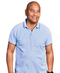 Fototapeta premium Hispanic middle age man wearing casual t shirt looking away to side with smile on face, natural expression. laughing confident.