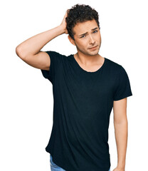 Obraz premium Young handsome man wearing casual black t shirt confuse and wonder about question. uncertain with doubt, thinking with hand on head. pensive concept.