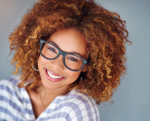 Obraz premium Portrait, smile and business woman in glasses isolated on a gray background. Face, happy professional in spectacles and young creative designer, entrepreneur and employee working at startup in Brazil