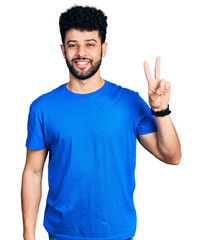 Young arab man with beard wearing casual blue t shirt showing and pointing up with fingers number two while smiling confident and happy.
