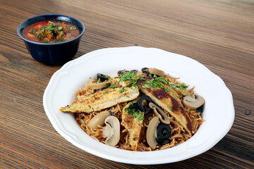 Chicken mushroom noodles with black olive and tomato sauce served in dish isolated on table side view of arabic food
