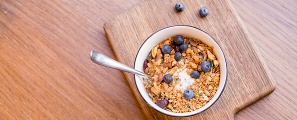 Fresh breakfast with greek yogurt nuts oatmeal granola with berries in a bowl on wooden background.selective focus. Healthy food, diet concept.