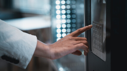 Close up hand of woman pushing button on vending machine for choosing a snack or drink. Small...