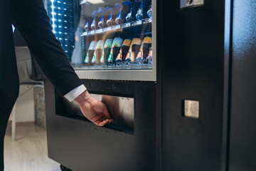 Close up hand of man pushing button on vending machine for choosing a snack or drink. Small...