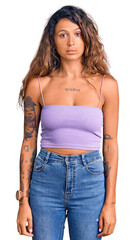 Fototapeta premium Young hispanic woman with tattoo wearing casual clothes relaxed with serious expression on face. simple and natural looking at the camera.