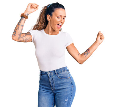 Young hispanic woman with tattoo wearing casual white tshirt dancing happy and cheerful, smiling moving casual and confident listening to music