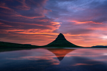 Dramatic colorful sky over Kirkjufell mountain reflected in the clear waters of a mountain lake during sunset. Amazing morning scene near Kirkjufell waterfall, Iceland. Landscape photography