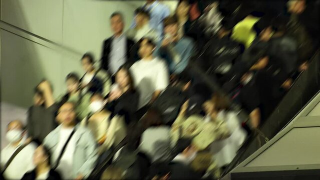 TOKYO, JAPAN - NOV 2023 : Crowd of people on the escalator at night. Shot in busy rush hour. Japanese people, tourists, diversity and lifestyle concept video. Blurred shot.