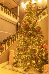 Fototapeta na wymiar tall Christmas tree and decorations in hotel lobby next to staircase 