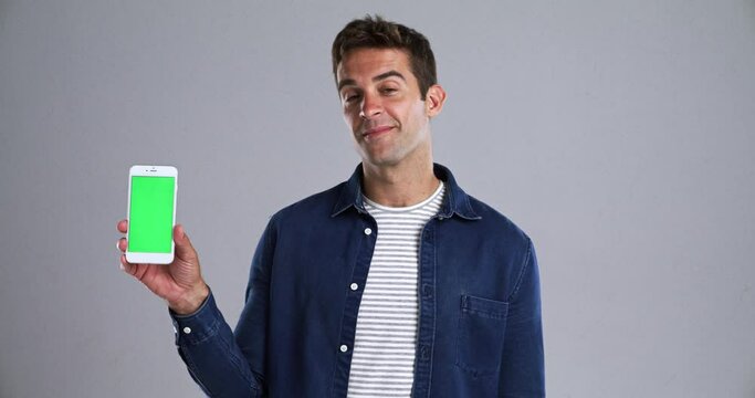 Man, face and green screen of phone for advertising space, sign up offer and newsletter in studio. Portrait, guy and mobile mockup for digital marketing, promotion and subscription on grey background