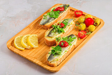 Wooden tray with marinated sardines canapés.