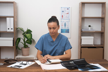 Medical Review: At her office desk, the doctor in a blue uniform focuses on the thorough review of...