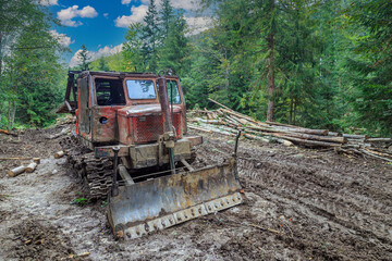 Old dozer on the dirty road in forest mountains