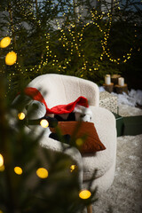 Christmas interior with a white sofa near green Christmas trees with lights that create a bokeh effect. two soft toy pandas with a red gnome hat on a white sofa.