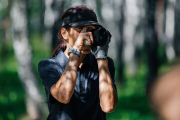 Female golfer looks into rangefinder and measures distance - obrazy, fototapety, plakaty