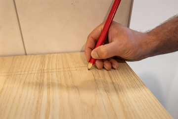 Marking a worktop with a lead pencil. The carpenter prepares the wooden part to saw it. Building a...