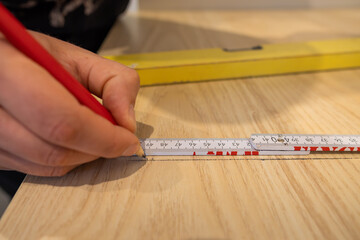 Marking a line with a pencil to saw the worktop board in a new kitchen. Carpenter working to...