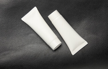 White tubes of cream on a leather surface
