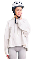 Beautiful brunette young woman wearing bike helmet and sporty clothes touching mouth with hand with painful expression because of toothache or dental illness on teeth. dentist