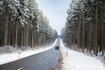Road through a snow covered forest, slippery and frosty street in winter, empty highway in cold...