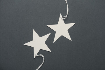 White tags on string in the shape of stars on dark gray background