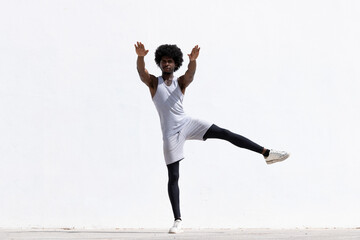 Serious black man stretching body over white wall