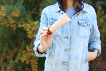Woman in denim jacket holding foundation tube outdoors