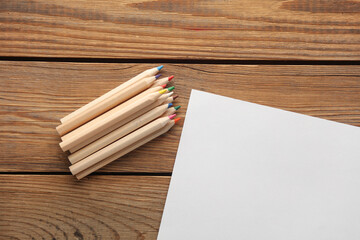 Obraz premium Wooden colored pencils and paper sheet on wooden background. Creativity, art