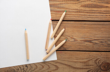 Wooden colored pencils and paper sheet on wooden background. Creativity, art