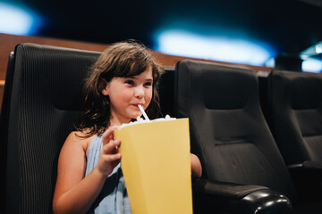 Girl with popcorn enjoying movie in theater