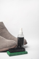 Fototapeta na wymiar Gray suede boots and water protection spray, brush on white background. Shoe care
