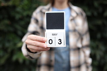Date May 3 block calendar woman holds outdoors