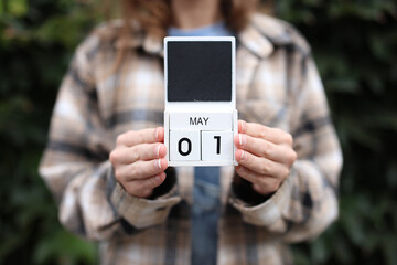 Date May 1 block calendar woman holds outdoors