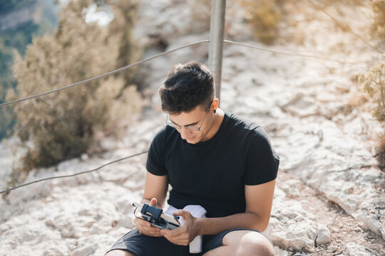 Male traveler holding drone controller on mountain