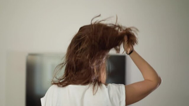 Woman runs at home adjusting hair against TV